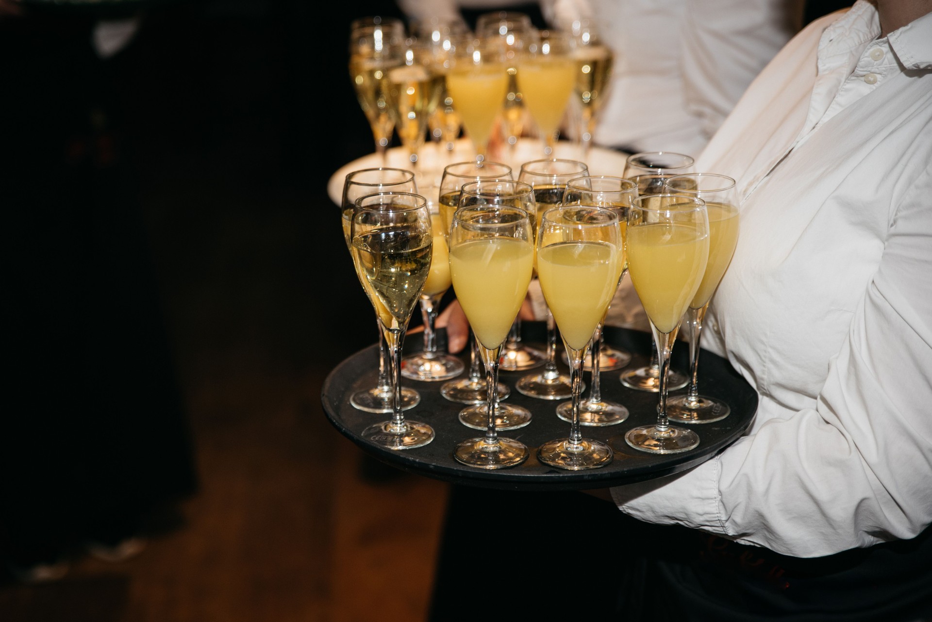 Server Carrying Champagne and Mimosa Cocktails on Tray at Event